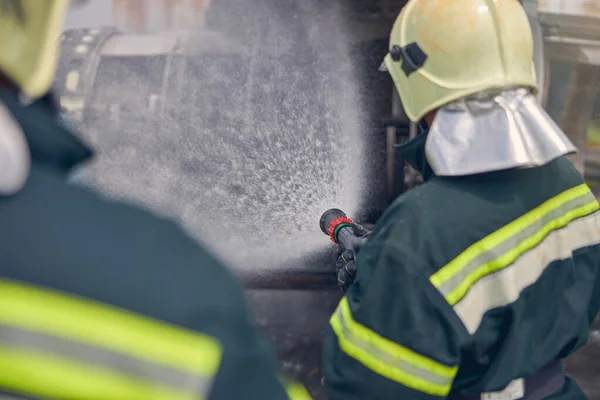Brandweerman met brandslang en spetterend water — Stockfoto