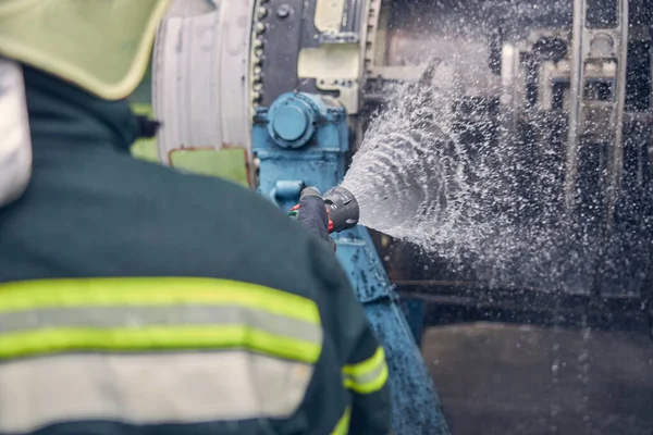 消防队员站在消防机旁边用软管浇水 — 图库照片