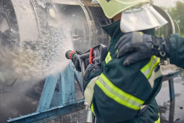 Homem vestindo uniforme de proteção aprendendo com equipamentos de incêndio — Fotografia de Stock