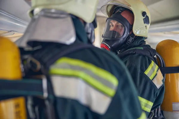 Two firemen with full equipments standing in the emergency place — Stock Photo, Image