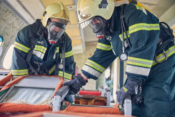 Brandmän i skyddsmasker och säkra hjälmar som utreder en nödplats — Stockfoto