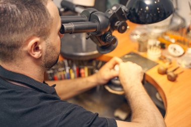 İşinde mikroskop kullanan zanaatkar.