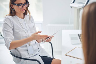 Dermatoloji kliniğinde siyah gözlüklü genç ve güzel bir doktor.