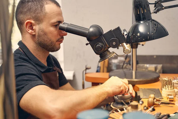 Joalheiro masculino sério usando uma ferramenta óptica — Fotografia de Stock