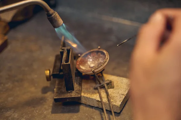 Joalheiro derretendo um pedaço de metal com uma lâmpada de sopro — Fotografia de Stock