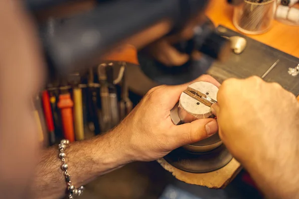 Male jeweler treating a workpiece with a metal tool — Stock Photo, Image