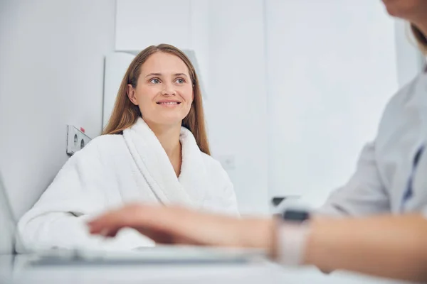 Усміхнений веселий клієнт клініки краси дивлячись на лікаря — стокове фото