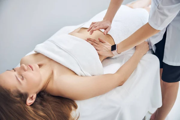 Hermosa mujer relajante mientras terapeuta haciendo masaje — Foto de Stock