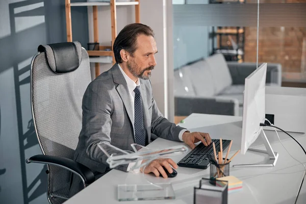 Homem sério usando computador moderno no trabalho — Fotografia de Stock