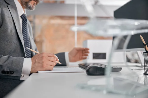 Männlicher Arbeiter schreibt im Büro in Spiralheft — Stockfoto