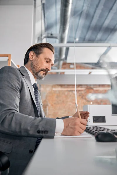 Hombre barbudo escribiendo en cuaderno en el trabajo — Foto de Stock