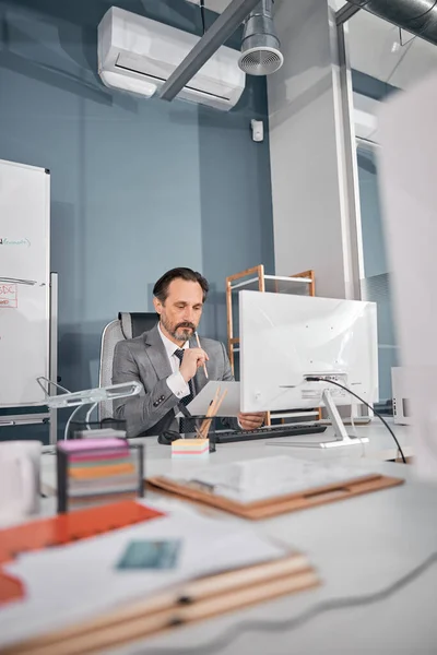 Bonito homem sério estudando documentos no trabalho — Fotografia de Stock