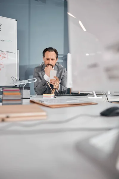 Homem barbudo usando smartphone moderno no trabalho — Fotografia de Stock