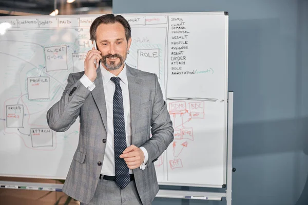 Hombre de negocios guapo hablando por celular en la oficina — Foto de Stock