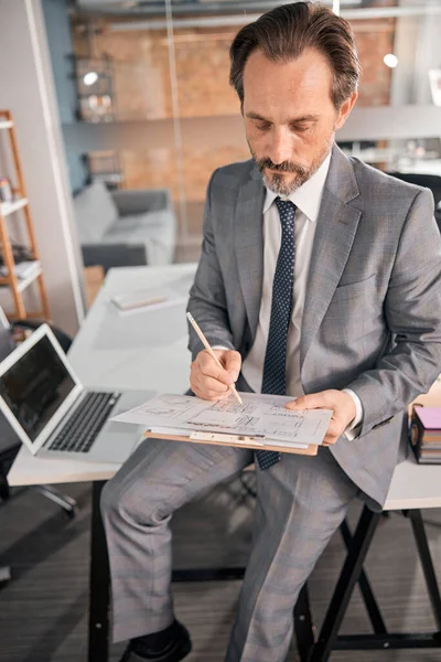 Hombre guapo escribiendo en el portapapeles en el trabajo — Foto de Stock