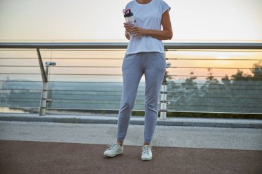 Female athlete standing on a pedestrian bridge clipart