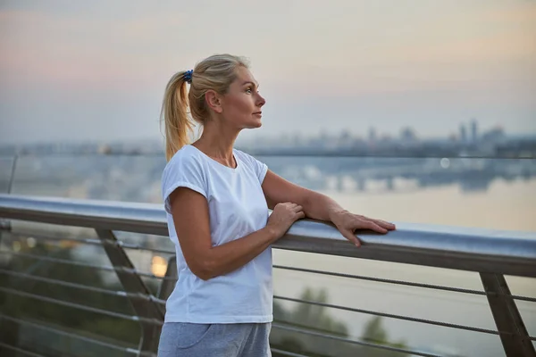 Pensive mulher desportiva inclinada sobre o corrimão — Fotografia de Stock