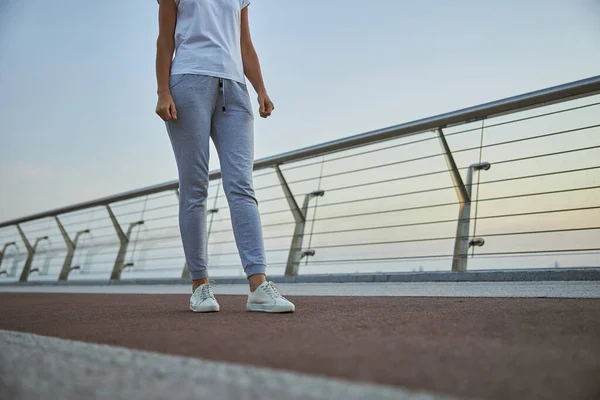 Sportlerin in stylischen Joggingschuhen auf einer Fußgängerbrücke — Stockfoto