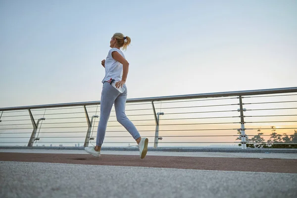 Mujer corriendo con una botella de plástico en la mano — Foto de Stock