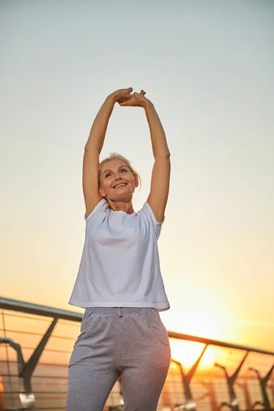 Cheerful mature blonde woman working out outside — Stock Photo, Image