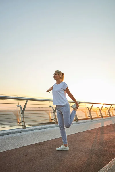 Deportiva mujer caucásica estirando los músculos de sus piernas — Foto de Stock