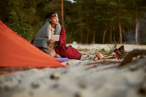 Schöne Reisende sitzt auf Sand am Lagerfeuer — Stockfoto