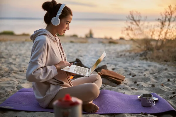Красивая молодая женщина в наушниках с ноутбуком на открытом воздухе — стоковое фото