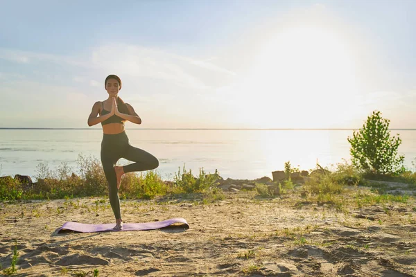 Giovane donna sportiva che pratica yoga sulla spiaggia — Foto Stock