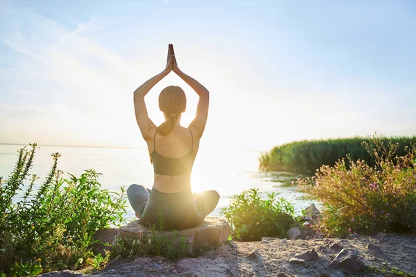 Sottile giovane donna che pratica yoga all'aperto vicino al mare — Foto Stock