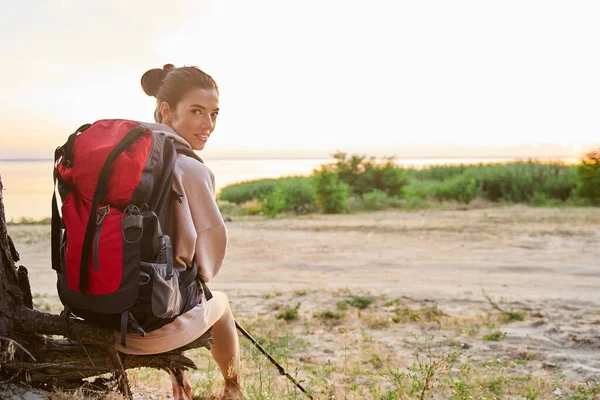 Beautiful female traveler sitting on tree bough — Stock Photo, Image