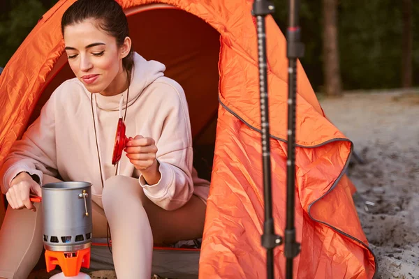 Charmante Reiseleiterin macht Heißgetränk beim Zelten — Stockfoto