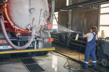 Yoğunlaşmış esmer kadın büyük turuncu fıçıyı yıkıyor.