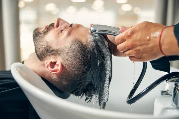 Tipo morena hombre disfrutando de proceso de lavado de cabeza — Foto de Stock