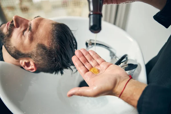 Zbliżenie męskiej dłoni wylewającej szampon — Zdjęcie stockowe