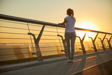 Güneş doğarken köprüde duran büyüleyici kadın.
