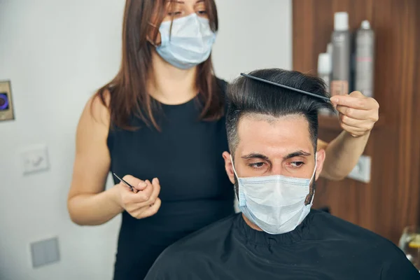 Προσεκτική γυναίκα που χτενίζει τα μαλλιά του πελάτη της — Φωτογραφία Αρχείου