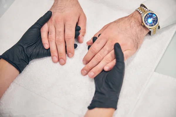 Primer plano del maestro de la manicura examinando las manos masculinas —  Fotos de Stock