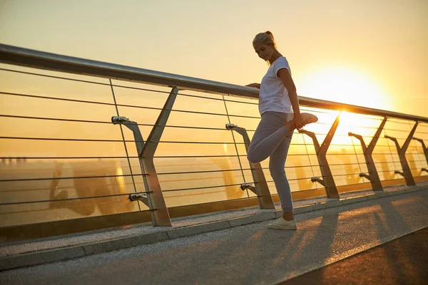 Güneş doğarken köprüde bacaklarını açan güzel bir kadın.