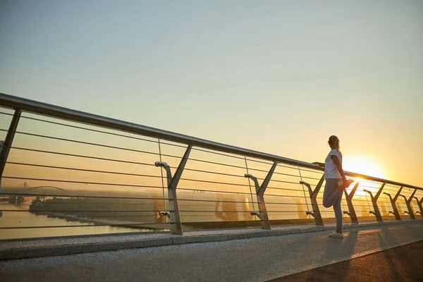 Köprüde bacaklarını açan sportif kadın.