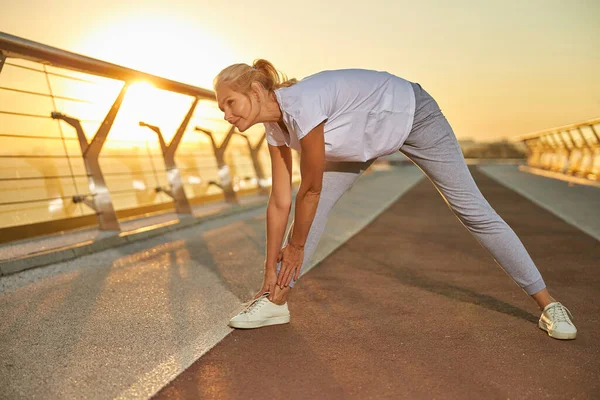 Beautiful woman stretching legs on the bridge — Stock Photo, Image