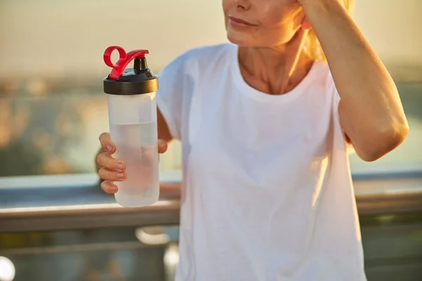 Middelbare vrouw in overhemd met fles water — Stockfoto