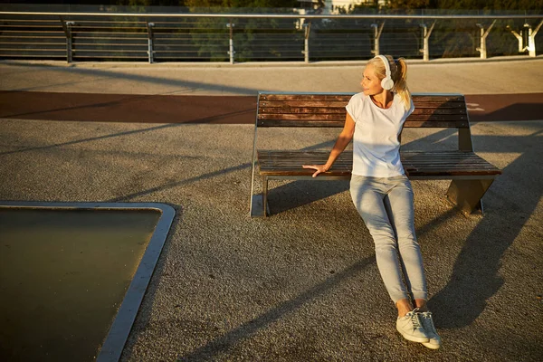 Очаровательная женщина в наушниках делает упражнения на улице — стоковое фото