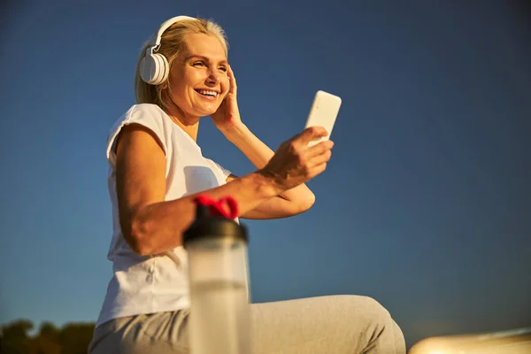 Hermosa mujer en auriculares usando el teléfono celular en la calle — Foto de Stock