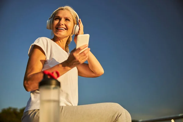 Mujer alegre en auriculares usando smartphone en la calle — Foto de Stock