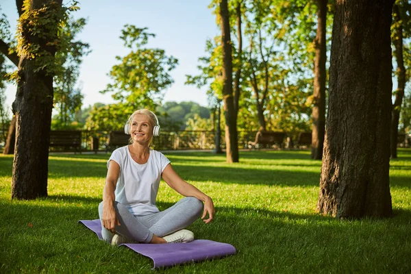 Joyful vrouw luisteren naar muziek via draadloze hoofdtelefoon in het park — Stockfoto