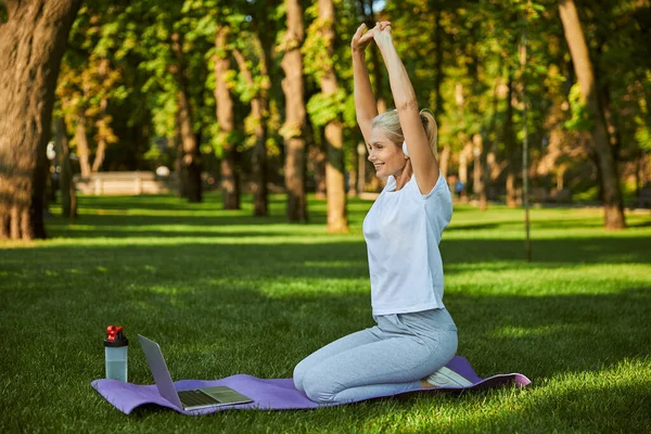 Charming woman using laptop during morning training in park — Stock Photo, Image