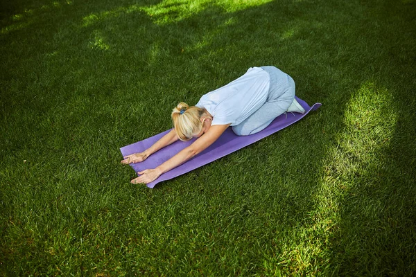 在阳光明媚的日子在公园练习瑜伽的金发女人 — 图库照片