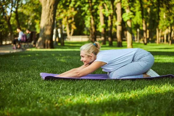 Vrolijke vrouw die yoga beoefent op zonnige dag in park — Stockfoto