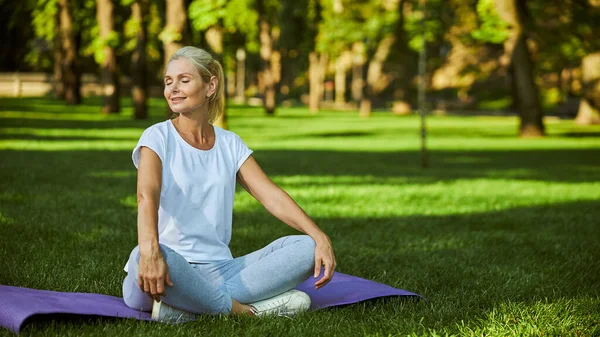 Mooie serene vrouw zittend op yoga mat buiten — Stockfoto
