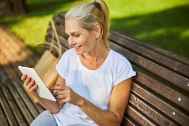 Sokakta tablet bilgisayar kullanan güzel, neşeli bir kadın.